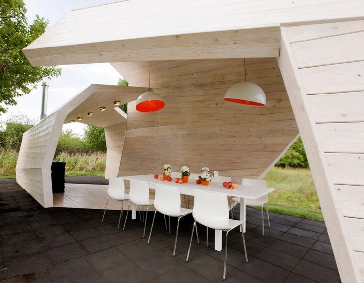 a minimalist dining area inside a sculptural pavilion with lights and a stylish minimal dining set in white