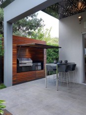 a minimalist outdoor bbq area with a dining set in black and a grill plus a cooker inside a wooden unit