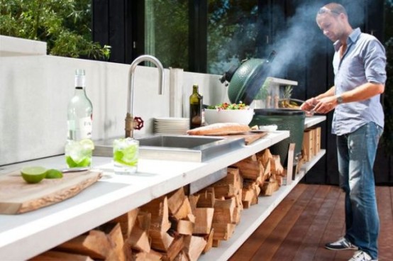 a contemporary outdoor kitchen with firewood storage, a sink, a cooking zone and a grill