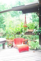 a vintage deck with a red lounger, a wooden chair and some potted greenery and blooms