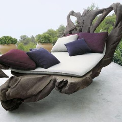 a unique dark wood lounger made of a single piece of driftwood looks abolutely natural, as if you've brought a piece of driftwood to your outdoor space