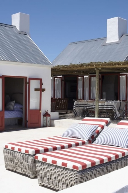 wicker loungers with striped upholstery and blue pillows are idea for a coastal or nautical space