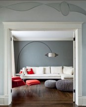 a stylish grey and creamy living room with graphite walls, a creamy sofa, a red chair and pillows and grey poufs