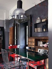a moody eclectic space with graphite grey walls, stained and black furniture and red chairs that make the space bold and contrasting