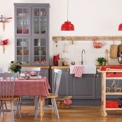 a Scandinavian kitchen with graphite grey cabinets, butcherblock countertops, white tiles, a dining set and lovely red details here and there