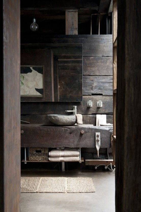 a wabi-sabi bathroom with weathered wood walls and a stone sinks plus a concrete floor