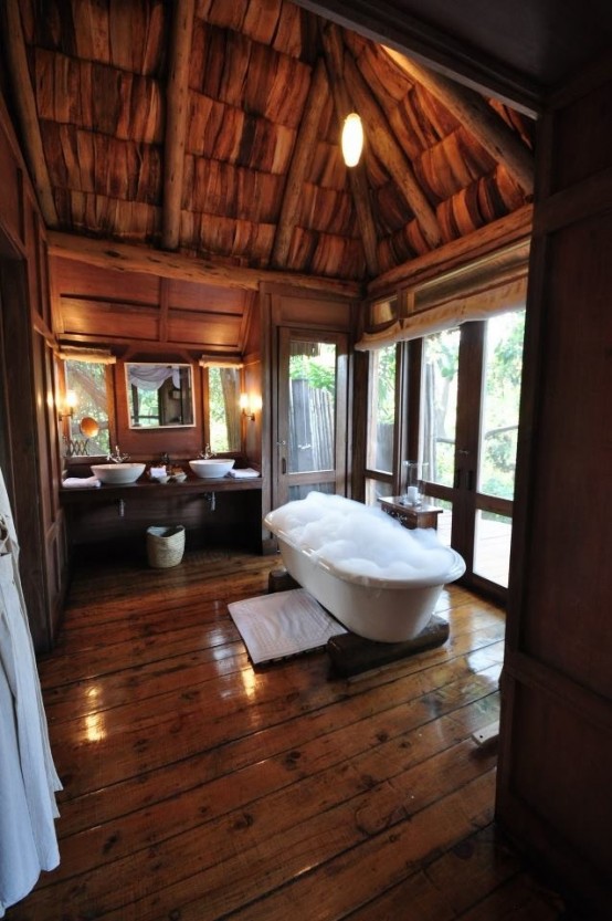a rustic bathroom with a glazed wall, a bathtub and skylights to enjoy natural light