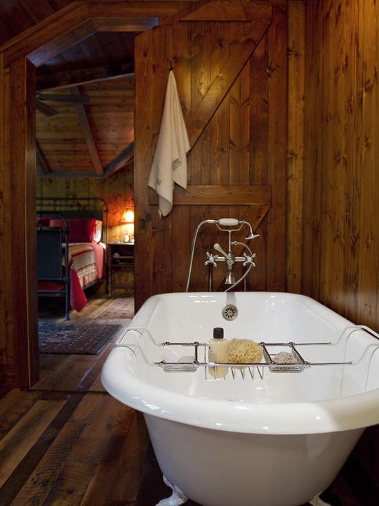 a rustic bathroom all clad with stained wood and a vintage bathtub