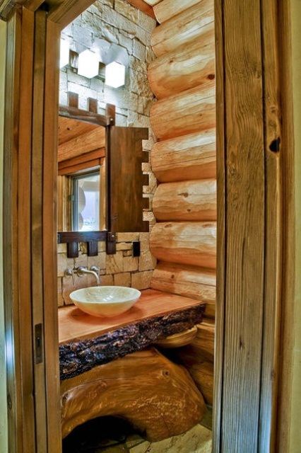 a light-colored wood clad bathroom with a natural stone wall