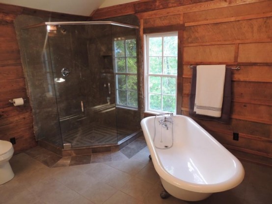 a rustic bathroom with wooden walls and a tile floor plus a glass clad shower space