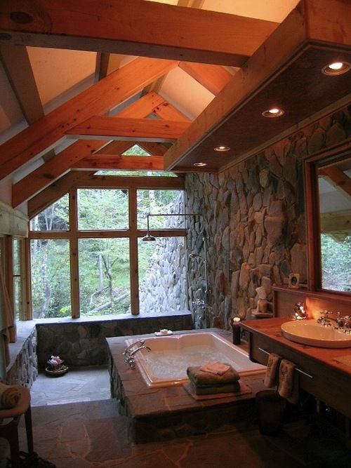 an attic chalet bathroom done with much natural stone and wood and with two glazed walls