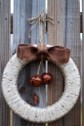 a yarn wrapped Christmas wreath with a brown bow and bells is a stylish rustic decoration