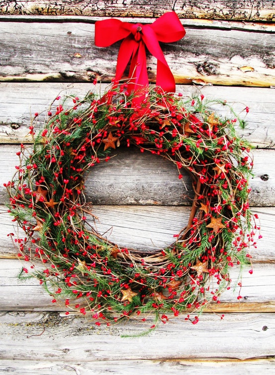 a Christmas wreath of greenery, vines and red berries plus a red ribbon bow for a rustic and cozy feel