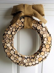 a rustic Christmas wreath of wood slices and a large burlap bow on top for a cozy and warm feel