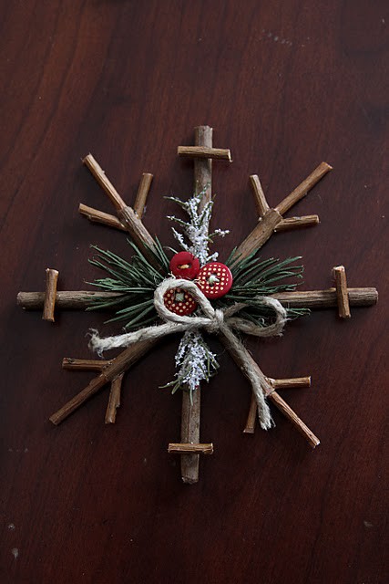 a rustic Christmas ornament of sticks, evergreens and red buttons for a cozy feel