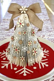 a rustic vintage Christmas tree of book pages, snowflakes and buttons and a large burlap bow on top