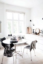 a small and airy Scandinavian dining nook with a round table and matching black chairs plus some vintage tableware is a very fresh solution