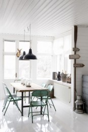 a shabby chic Nordic dining room with a stained wooden table, matching turquoise chairs, black pendant lamps and some decor