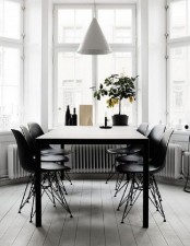 a modern dining space by the window, with a black table, black matching chairs and a white cone pendant lamp plus a lemon tree