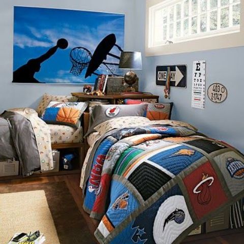 a bright sporty shared teen bedroom with blue walls, a poster, simple beds with bright sporty bedding