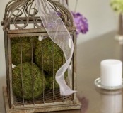 a cage with moss balls and ribbons on top looks very chic, vintage and elegant