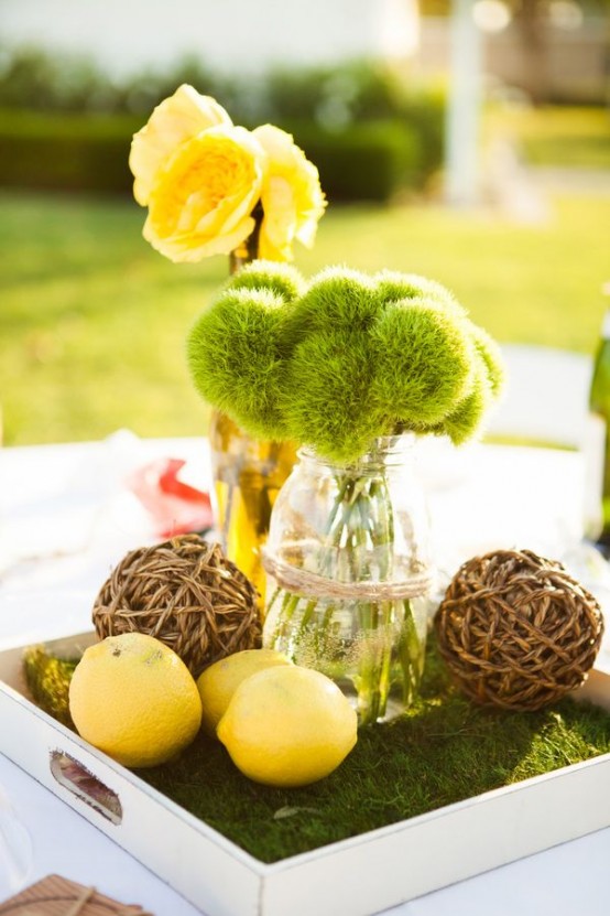 a bright spring centerpiece fo a tray covered with moss, lemons, vine balls and a moss and bloom arrangement
