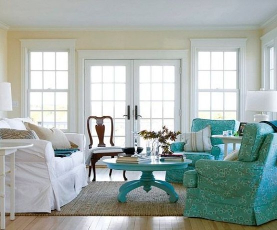 a neutral living room with a vintage touch, light yellow walls, a white sofa, turquoise chairs and a coffee table and a vintage dark-stained chair