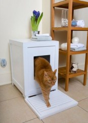 a small white box with a cat litter box and a wooden mat in front of it is a cool piece for a bathroom or powder room