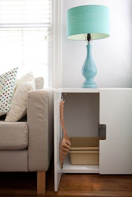 a white cabinet with a cat litter box inside and a shovel on the door is a simple and elegant solution