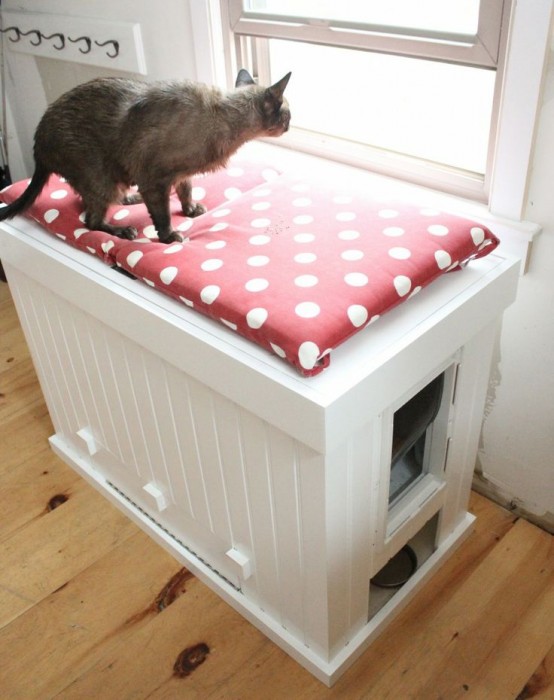 a white storage cabinet with a polka dot cushion on top and a cat litter box inside