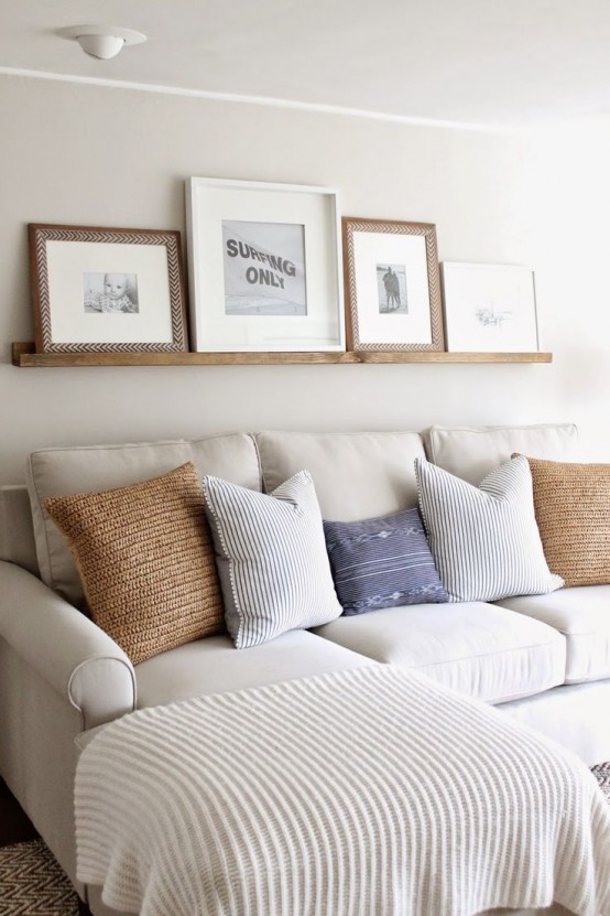 a neutral farmhouse living room done with a wooden ledge and artworks in wooden and woven frames is a very cozy and cool space