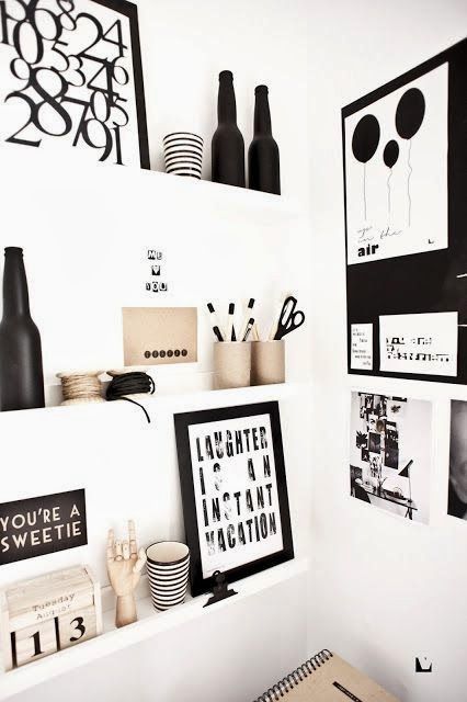 a small nook made useful with white ledges, with black and white artworks, photos, figurines, decor looks cool