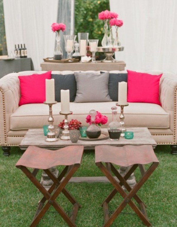 a modern neutral terrace with a sofa, a coffee table, leather stools and a console table spruced up with bright pink touches
