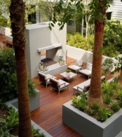 a modern tropical terrace with a two side fireplace, stylish modern furniture, potted plants and even palm trees around