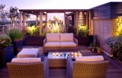 a modern rooftop terrace with wicker sitting furniture, potted blooms and greenery, candles and lights and gorgoeus views