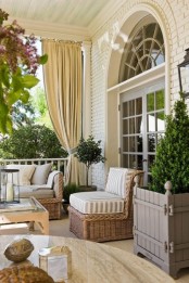 a modern neutral terrace with a Mediterranean feel, with potted greenery and plants, with wicker and wooden furniture