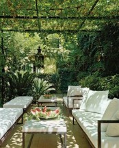 a modern tropical terrace done with white upholstered furniture, with greenery and tropical trees all around and lanterns
