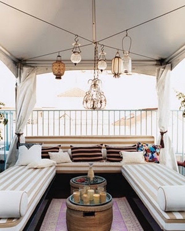 a modern take on a boho Moroccan terrace with striped sofas, pillows and a large Moroccan chandelier with lanterns