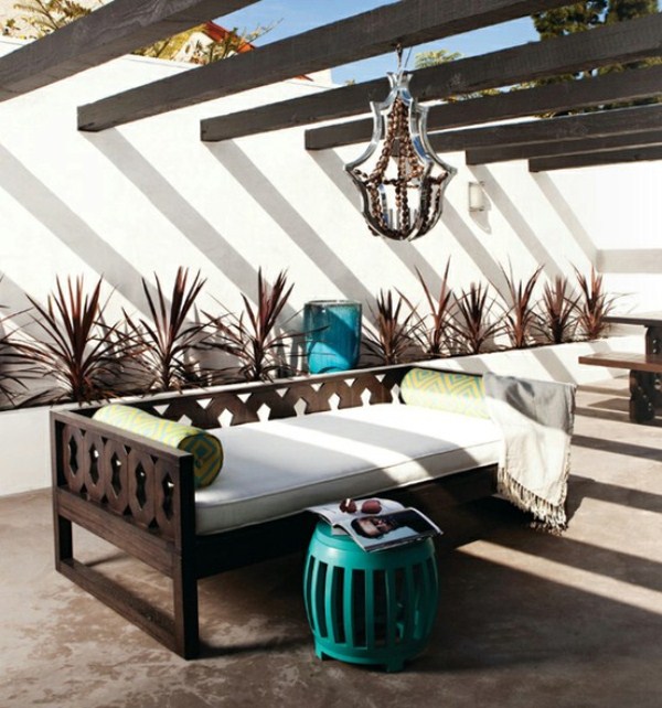 a bold modern space with dark stained wooden beams, a catchy chandelier, a carved wooden bench and a turquoise table