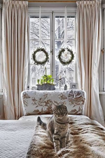 a faux fur throw, elegant curtains and wreaths hanging on the windows for an elegant wintry bedroom