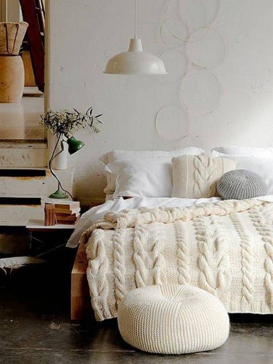 white knit bedding and pillows and an ottoman make the bedroom more winter-like and very chic