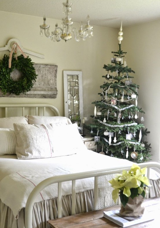 a neutral bedroom dressed up for a Christmas tree with ornaments and a greenery wreath and with potted blooms