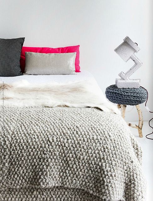 bring a cozy winter feel to your bedroom with knit blankets and pillows, a knit side table and a faux fur throw