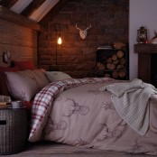 mauve and plaid bedding with deer prints, a knit blanket and some firewood in crates make the bedroom winter-ready and cozy