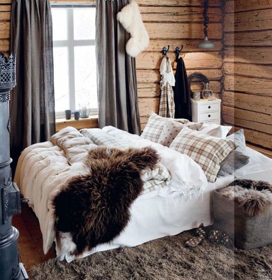 plaid pillows, faux fur rugs and blankets, a fur ottoman and stocking make this cabin bedroom super welcoming