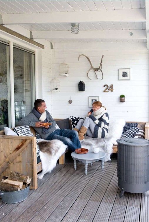 a farmhouse winter terrace with a wooden sectional, lots of mismatching pillows and faux fur, a heart and a vintage side table plus a gallery wall