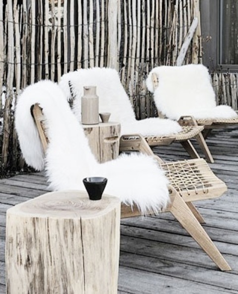 a wabi-sabi winter terrace with woven chairs, white faux fur, a tree stump as a side table is a lovely and relaxed space