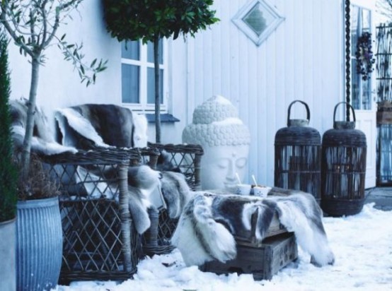 an eclectic winter terrace with woven chairs covered with faux fur, oversized lanterns, potted plants and statuettes