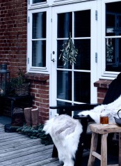 a lovely winter terrace done with some wooden furniture, a Christmas tree and some faux fur and blankets is welcoming
