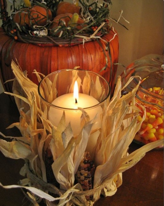 a pillar candle in a candleholder wrapped with corn husks and corn cobs is very rustic and very cozy